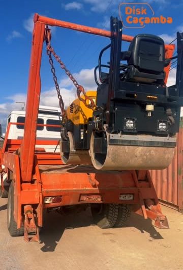 Caminhão da Disk Caçamba transportando um rolo compactador